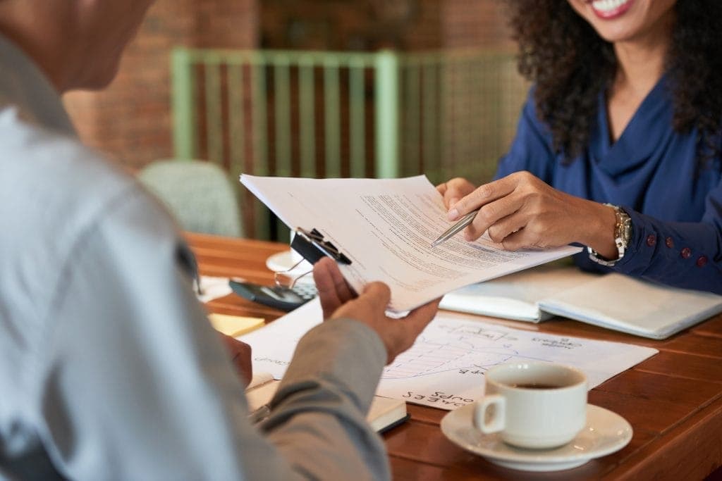 Property manager reviewing a contract with a client at a table for property service and management