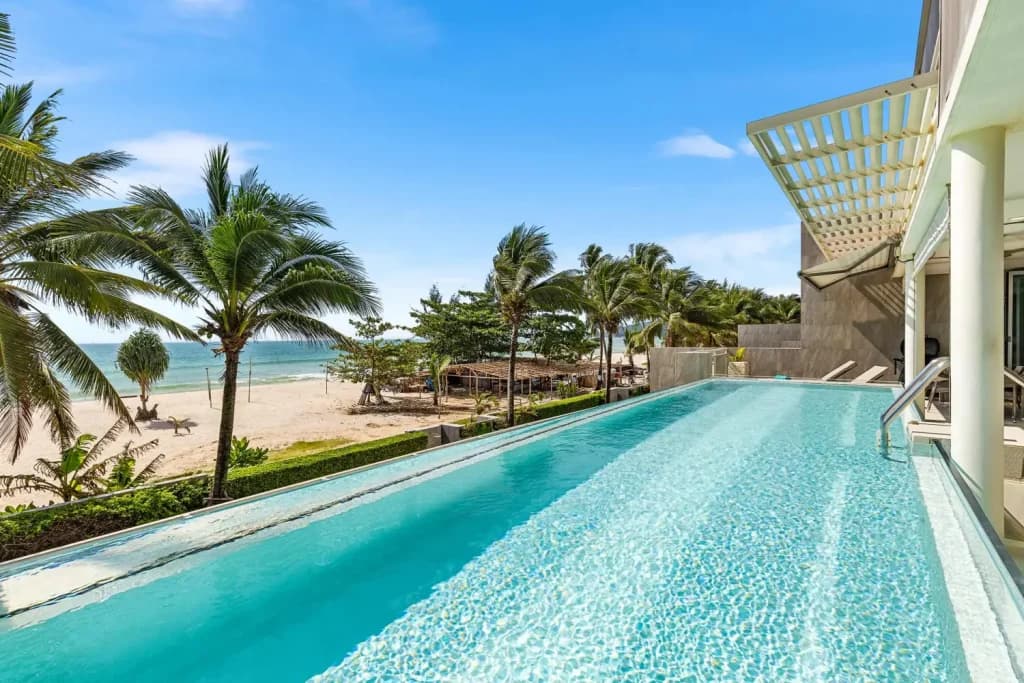 Piscina a sfioro con vista su una spiaggia tropicale con palme a Phuket, Thailandia
